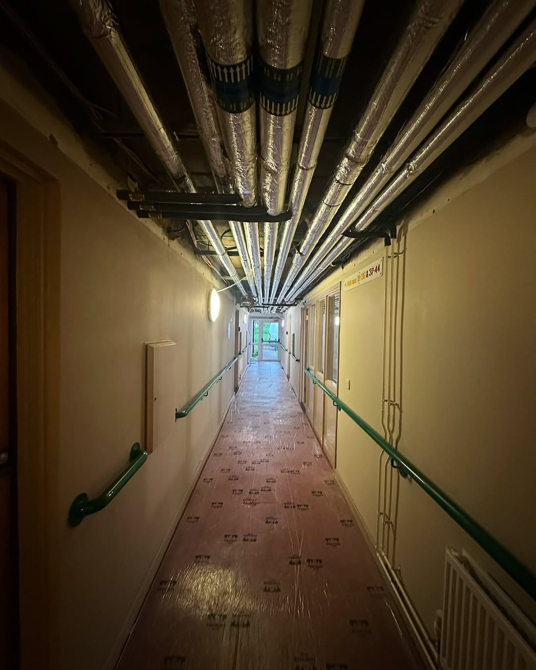 Foil-faced insulated pipework spanning the full length of a residential corridor  -  Sheffield care home